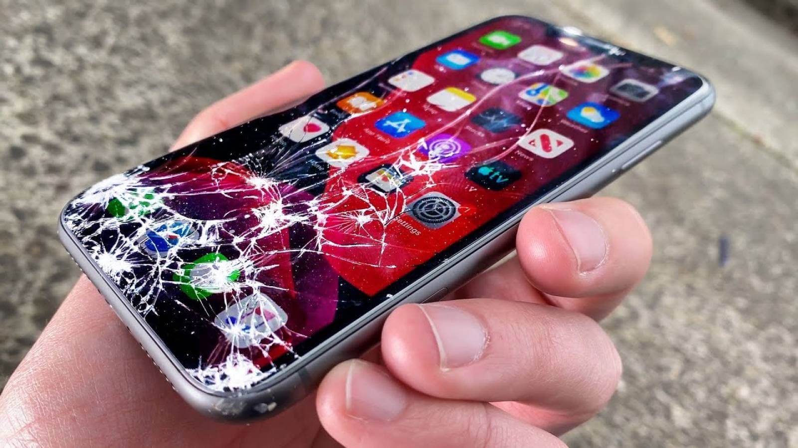 iPhone tenu en main, l'écran brisé par une chute